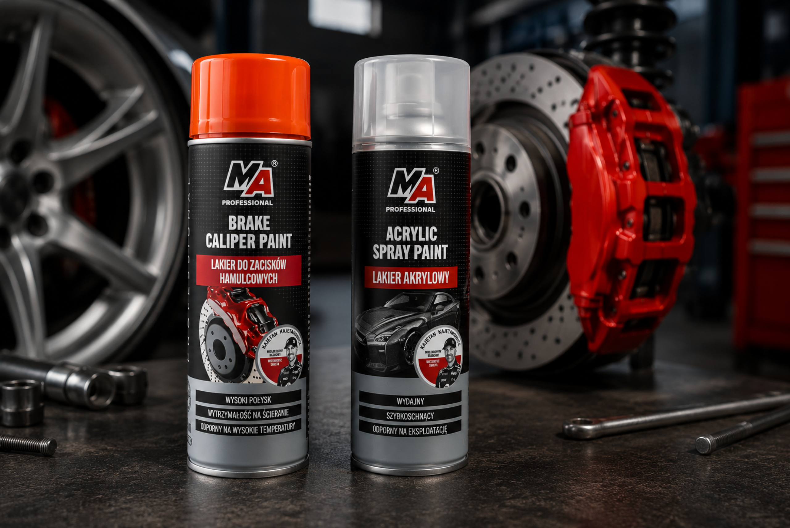 Dwa lakiery techniczne MA Professional w sprayu do zastosowań motoryzacyjnych, ustawione w warsztacie przy tarczy hamulcowej, czerwonym zacisku i feldze.